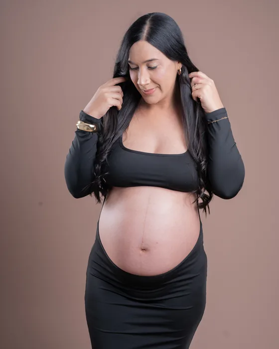 Gestante em vestido preto olhando para a barriga